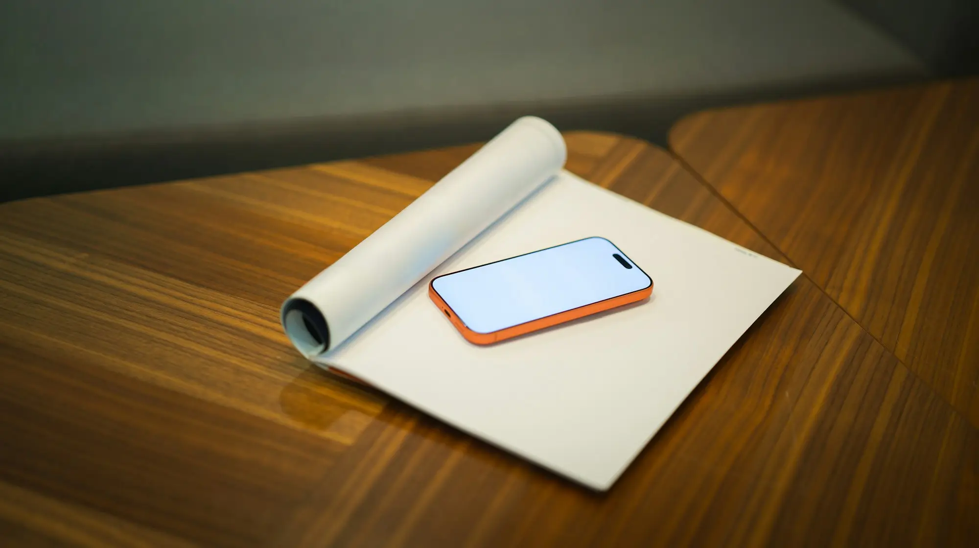 Phone and rolled-up plans on a table for reviewing repayments